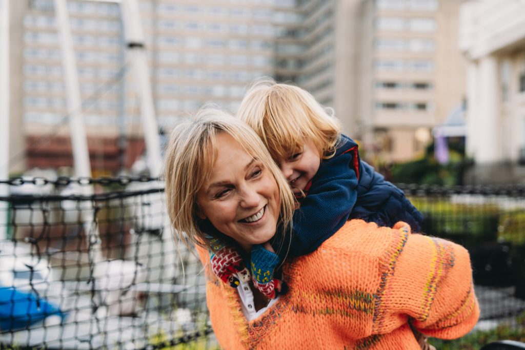 Grandmother carrying her grandson on her shoulders smiling and having fun