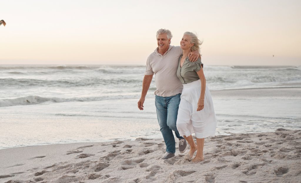 Mature married couple walking on the beach