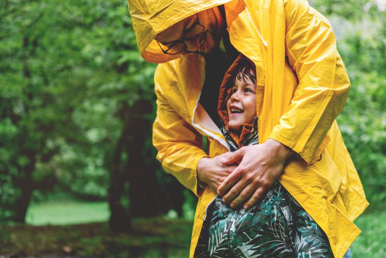 father protecting son from rain